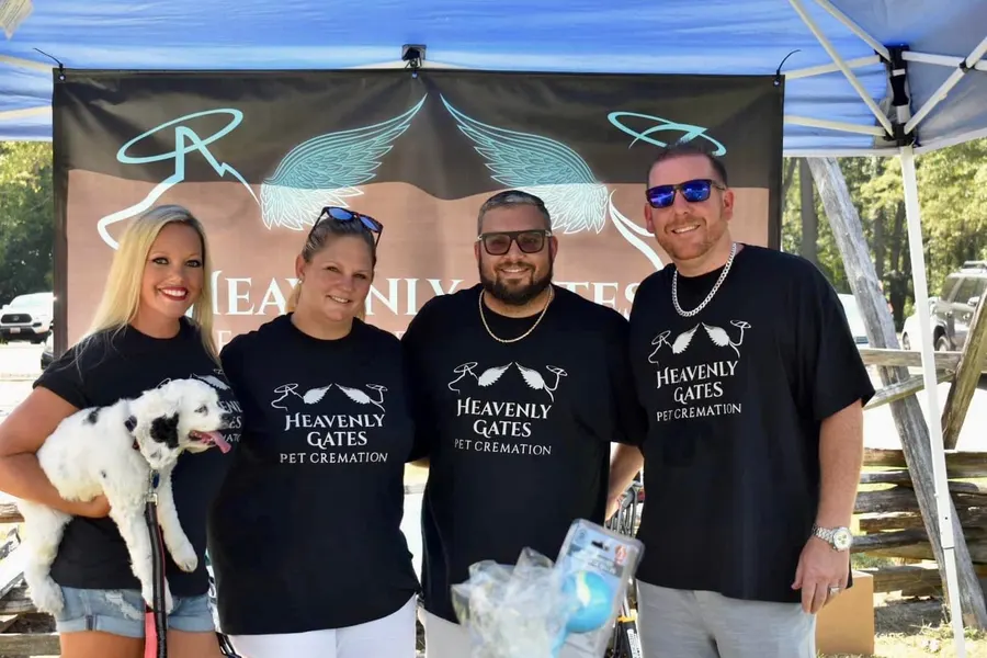 The Heavenly Gates team in matching shirts at Paws on Pemberton, holding a black and white dog.