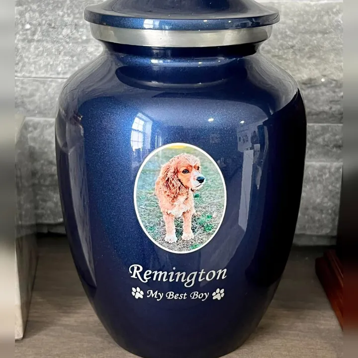 A glossy blue urn with an oval photo of a spaniel and the dog’s name below it.