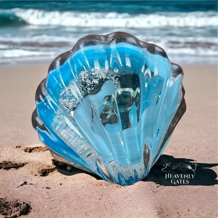 A blue glass seashell resting on a sandy beach.