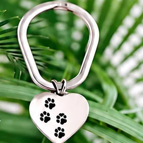 A silver heart keychain with black paw prints.