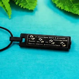A black bar pendant engraved with a poem and paw prints, on a black cord.