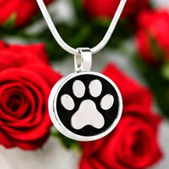 A round black pendant with a silver paw print.