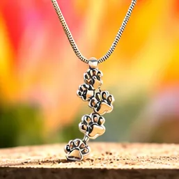 A silver pendant of paw prints falling in a line.