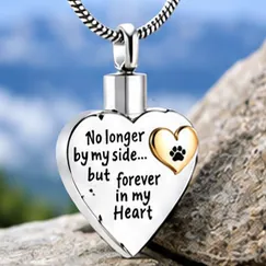 A silver heart pendant engraved No longer by my side, but forever in my heart, with a small gold heart.