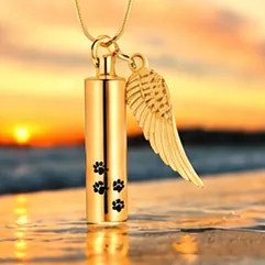A gold cylinder pendant with paw prints and an angel wing charm.
