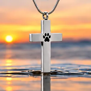 A silver cross pendant with a black paw print.