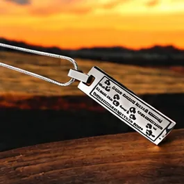 A silver bar pendant engraved with a poem and paw prints.