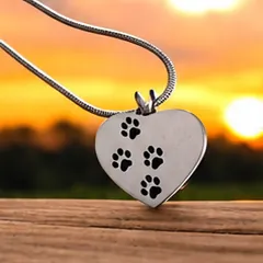 A silver heart pendant with three black paw prints.