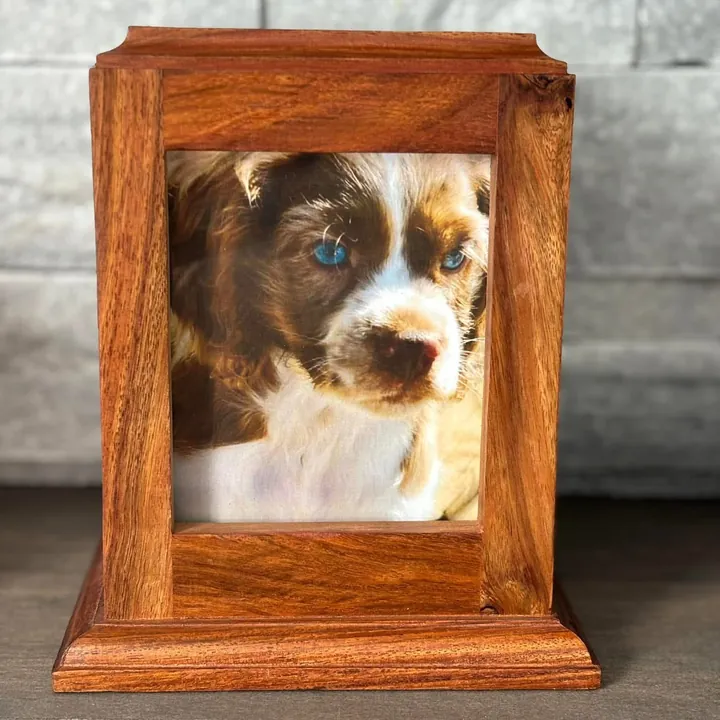 An upright wooden urn with a photo of a puppy in its front frame.