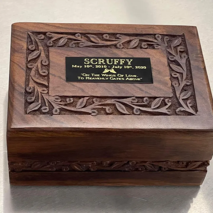 A carved rosewood box with a leaf border and an engraved name plate on the lid.